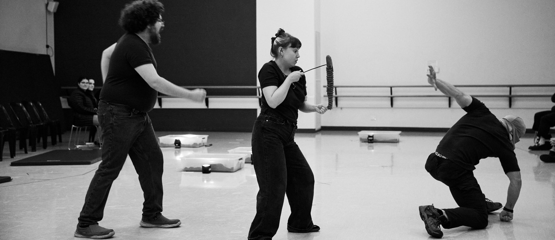 The Dig in rehearsal — three performers mid-scene with a cardboard trilobite
